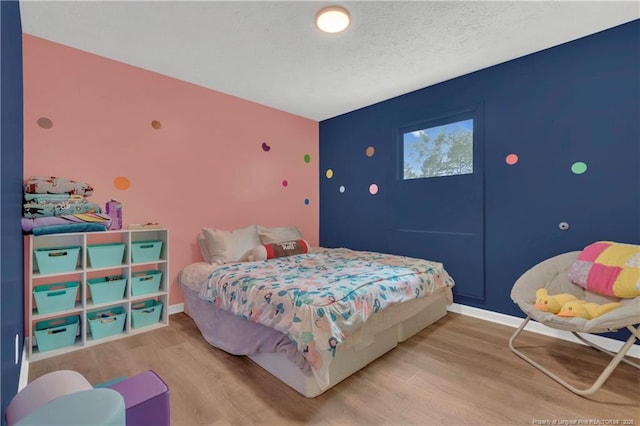 bedroom with baseboards, a textured ceiling, and wood finished floors