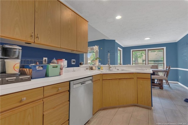 kitchen featuring a sink, stainless steel dishwasher, a peninsula, and light countertops