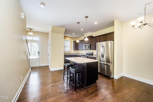 kitchen featuring appliances with stainless steel finishes, dark brown cabinetry, a kitchen island, a breakfast bar, and a sink
