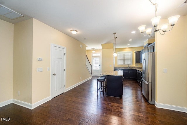 kitchen with stainless steel appliances, a breakfast bar, dark wood-style floors, a kitchen island, and baseboards