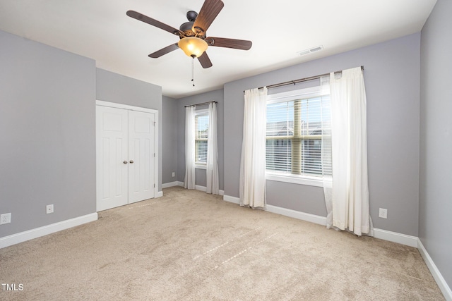 unfurnished bedroom with carpet floors, baseboards, a closet, and a ceiling fan