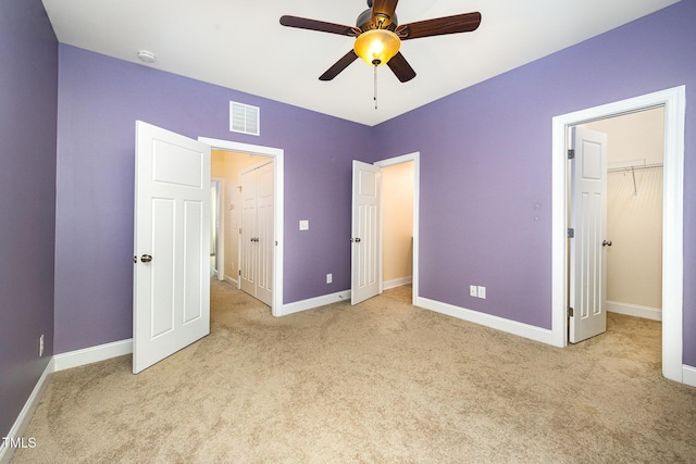 unfurnished bedroom with carpet, a closet, baseboards, and a walk in closet