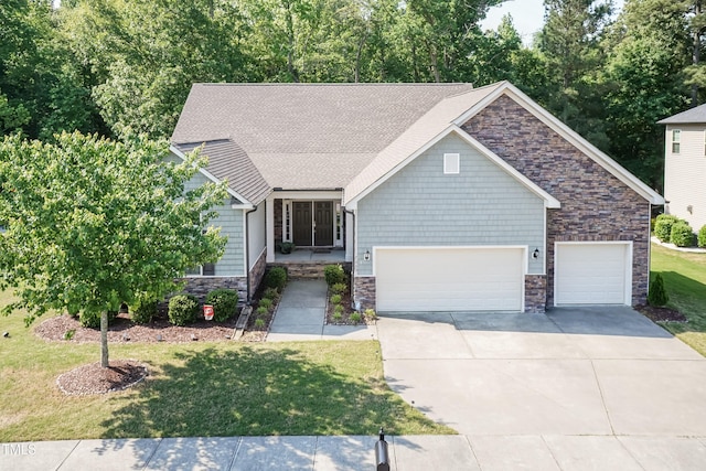 craftsman house featuring stone siding, an attached garage, a front yard, and concrete driveway