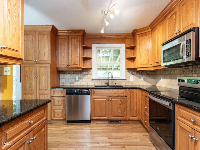 kitchen featuring appliances with stainless steel finishes, open shelves, a sink, brown cabinets, and light wood finished floors