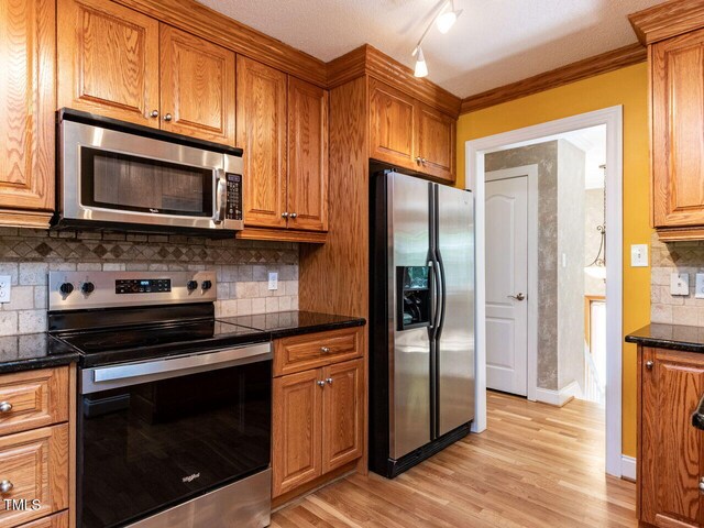kitchen with stainless steel appliances, brown cabinets, light wood-style floors, backsplash, and crown molding