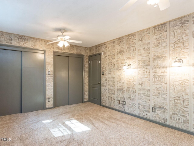 unfurnished bedroom with elevator, two closets, carpet, ceiling fan, and wallpapered walls