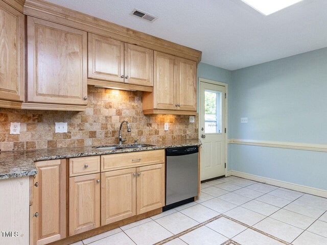 kitchen with dishwasher, a sink, backsplash, light tile patterned flooring, and stone counters