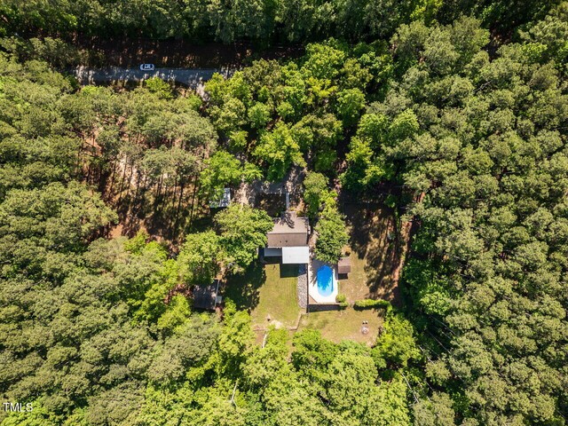 aerial view of a pool and a heavily wooded area