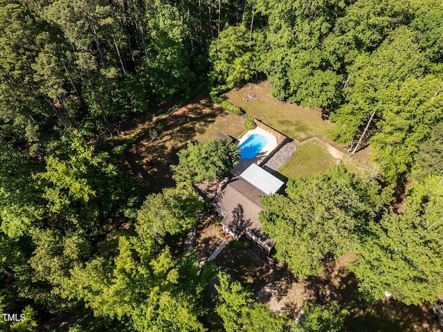 aerial view of property and surrounding area with a pool area and a heavily wooded area