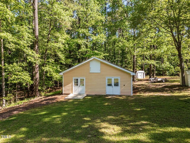 rear view of house with an outdoor structure, a lawn, and a storage shed