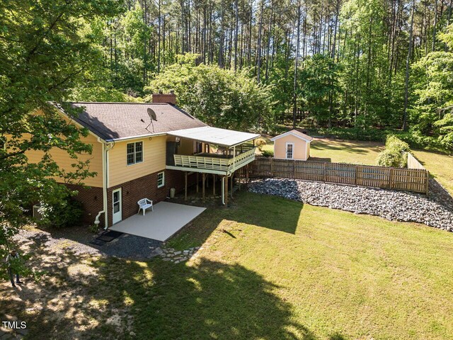 rear view of property with a patio, a deck, a chimney, a yard, and brick siding