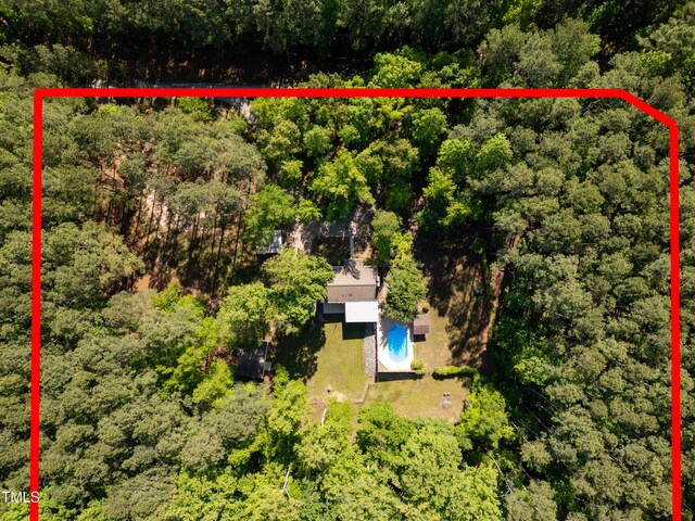 view from above of property with property boundaries highlighted, a heavily wooded area, and a pool area