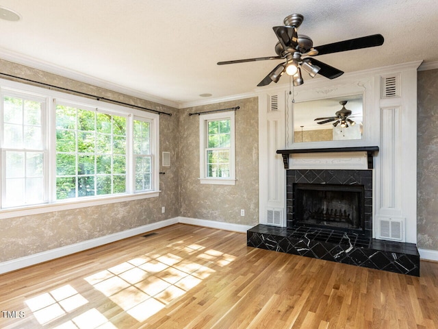 unfurnished living room with wood finished floors, baseboards, ornamental molding, a ceiling fan, and a tile fireplace