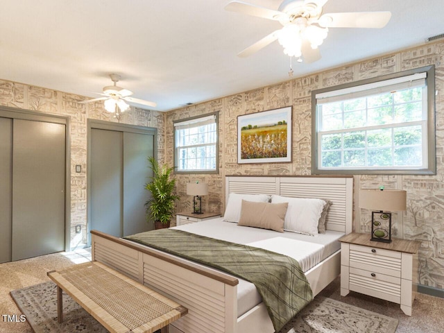 bedroom with multiple closets, carpet, and a ceiling fan