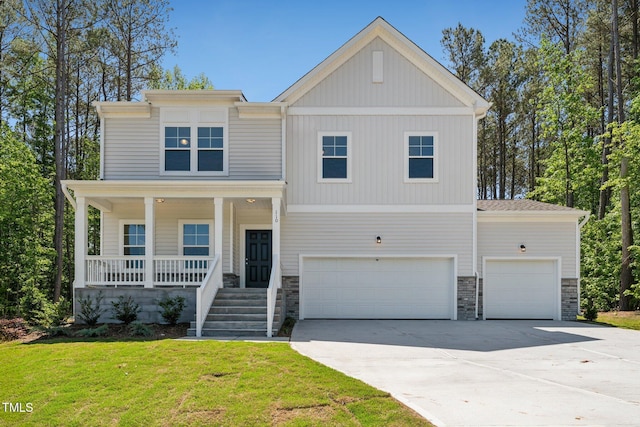 view of front of home with driveway, a front lawn, covered porch, stone siding, and a garage