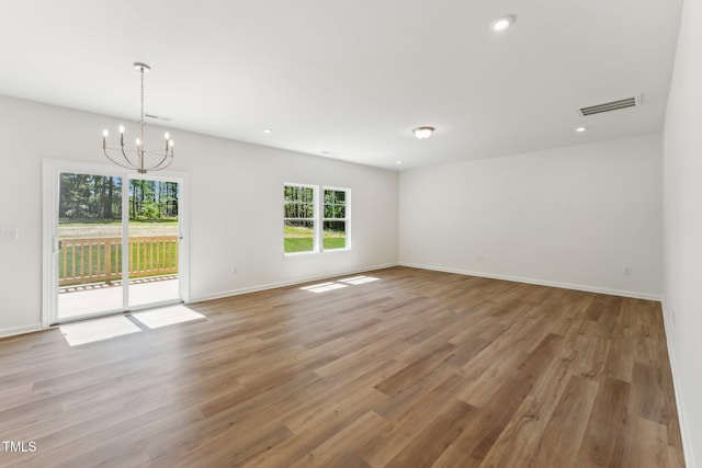 empty room with a chandelier, light wood-style flooring, baseboards, and recessed lighting