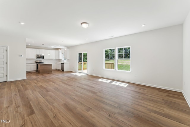 unfurnished living room with wood finished floors, baseboards, and recessed lighting