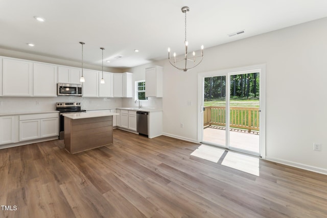 kitchen featuring stainless steel appliances, a chandelier, decorative backsplash, baseboards, and white cabinetry