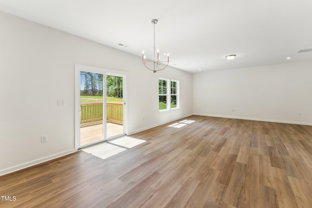 unfurnished dining area featuring a chandelier, light wood-type flooring, and baseboards