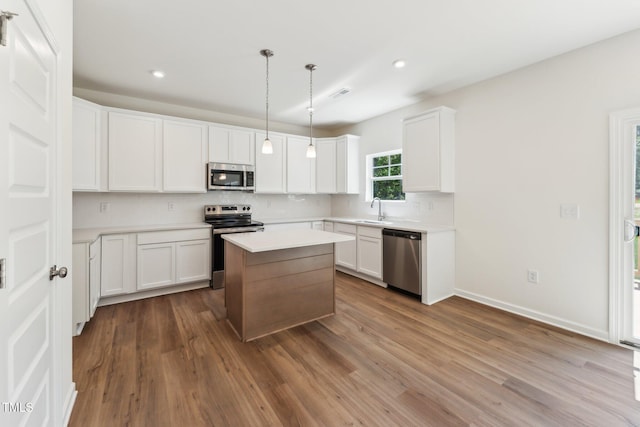 kitchen featuring appliances with stainless steel finishes, a sink, decorative backsplash, a kitchen island, and white cabinets
