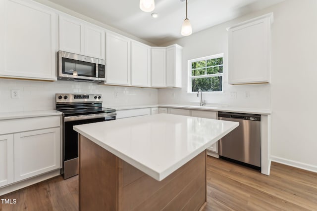 kitchen featuring stainless steel appliances, wood finished floors, decorative backsplash, and light countertops