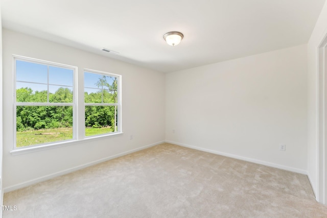 empty room featuring light colored carpet and baseboards