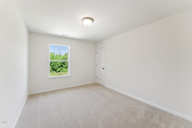 spare room with light colored carpet and baseboards