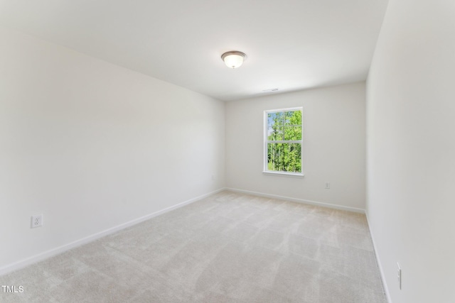 empty room featuring light colored carpet and baseboards