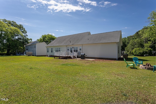rear view of house with an outdoor fire pit, a deck, and a yard