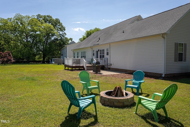 back of house featuring a fire pit, a wooden deck, a yard, and roof with shingles