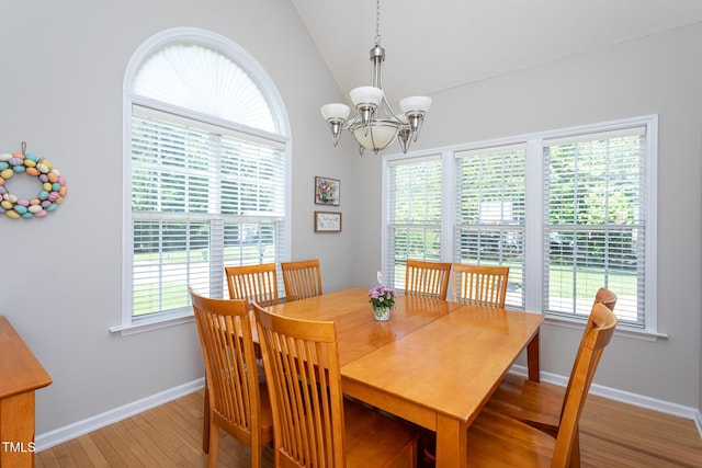 dining area featuring healthy amount of natural light, a chandelier, light wood-type flooring, lofted ceiling, and baseboards