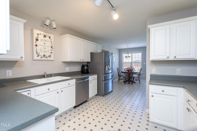 kitchen featuring appliances with stainless steel finishes, a sink, white cabinetry, and dark countertops
