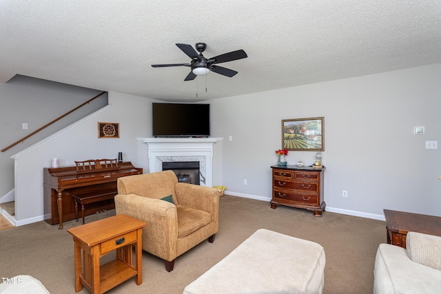 living area with ceiling fan, light colored carpet, a fireplace, a textured ceiling, and stairway
