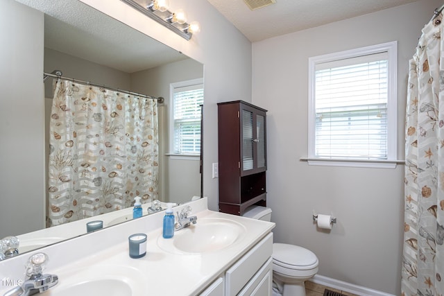 bathroom featuring toilet, double vanity, and baseboards