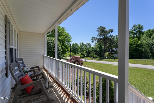 balcony with covered porch and view of scattered trees