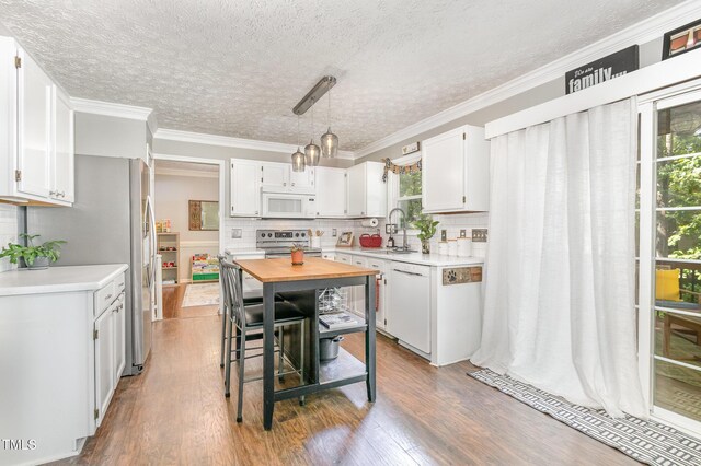 kitchen featuring appliances with stainless steel finishes, a sink, wood finished floors, backsplash, and a textured ceiling