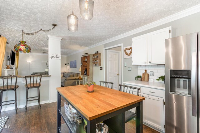 dining space featuring dark wood-type flooring, a textured ceiling, and ornamental molding