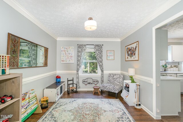 sitting room with a textured ceiling, wood finished floors, baseboards, and ornamental molding