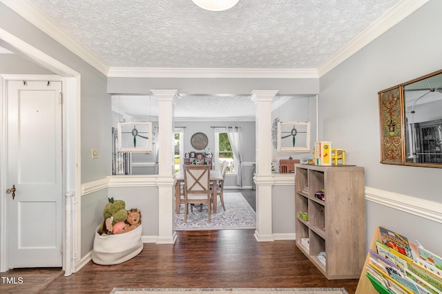 entrance foyer with ornate columns, wood finished floors, a textured ceiling, ornamental molding, and baseboards