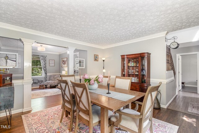 dining area featuring decorative columns, wood finished floors, crown molding, baseboards, and a textured ceiling