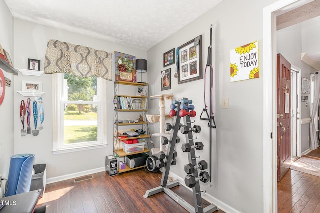 workout area featuring wood-type flooring, baseboards, and a textured ceiling
