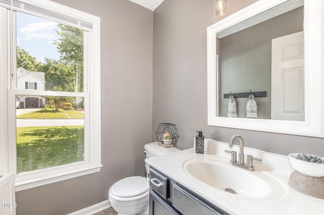 half bath with toilet, vanity, and baseboards