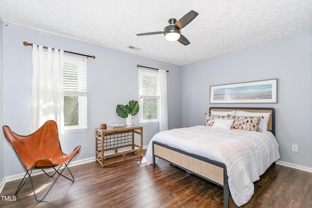 bedroom with wood finished floors, a textured ceiling, baseboards, and a ceiling fan