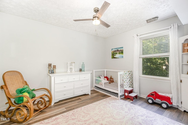 bedroom with a textured ceiling, wood finished floors, and a ceiling fan