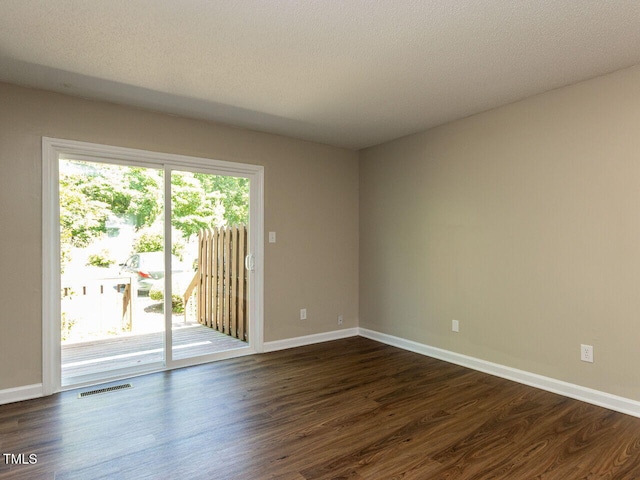spare room featuring dark wood-style flooring and baseboards