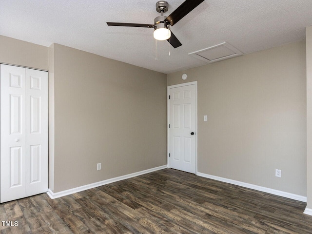 unfurnished bedroom featuring attic access, dark wood-style floors, baseboards, a closet, and a textured ceiling