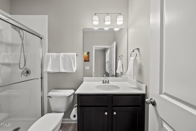 full bath featuring a stall shower, vanity, toilet, and baseboards
