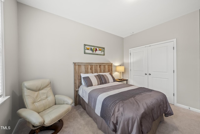 carpeted bedroom with a closet and baseboards