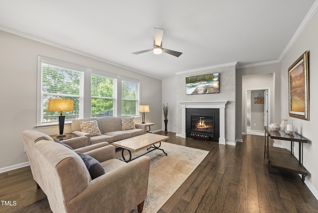 living room with a ceiling fan, a glass covered fireplace, ornamental molding, dark wood-style flooring, and baseboards
