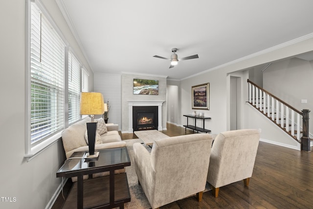 living area featuring dark wood-type flooring, crown molding, baseboards, healthy amount of natural light, and stairs